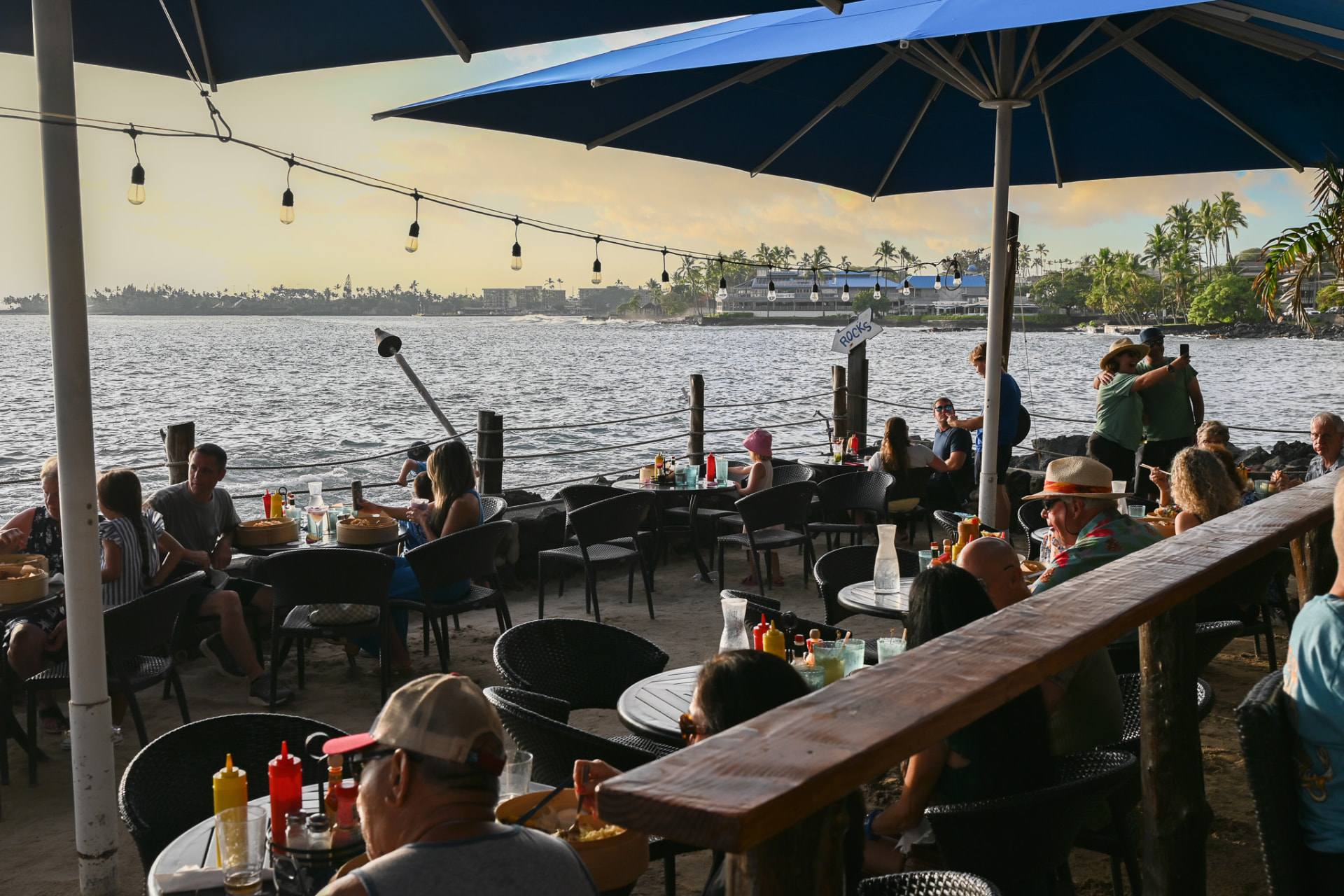 Guests dining on the sand at On the Rocks overlooking Kailua Bay